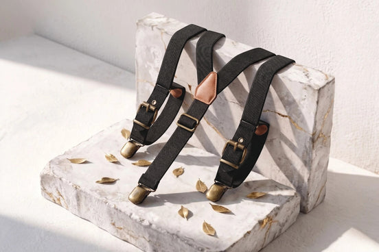 Bretelles ajustables noires en tissu élastique avec détails en cuir et pinces métalliques dorées, style rétro chic.