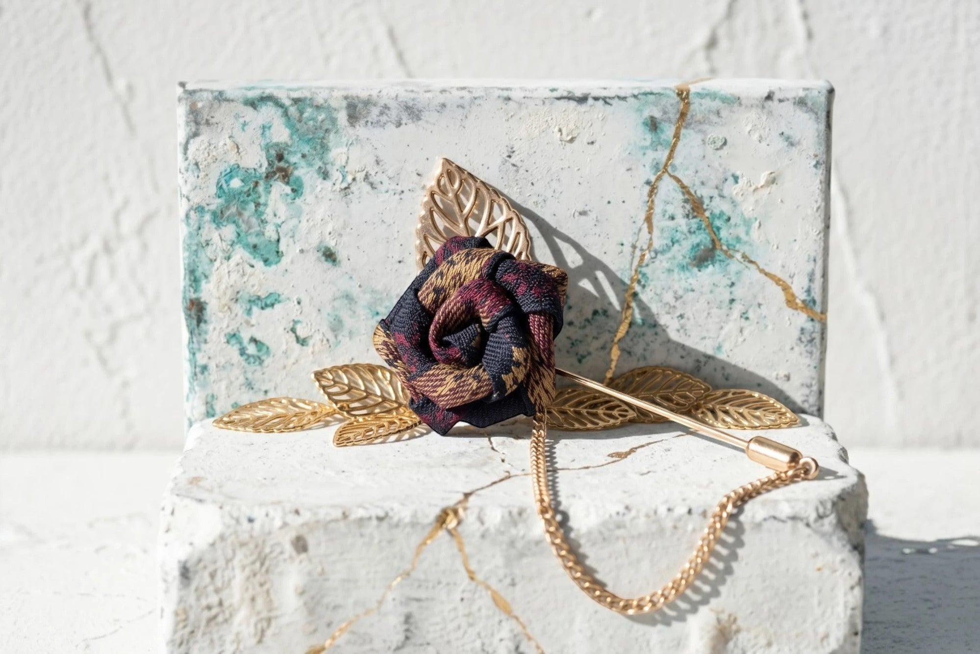 Broche épingle Roaring 20s Paris en forme de rose, tissu à carreaux bordeaux et bleu marine, avec chaîne et feuilles dorées.