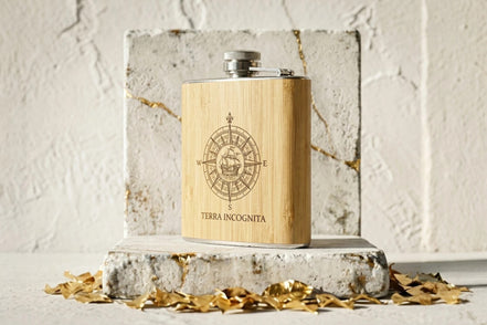 Flasque à whisky Roaring 20s Paris en acier et bois clair, gravée d'une rose des vents et du texte 'TERRA INCOGNITA'.