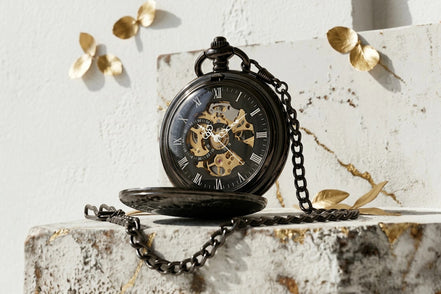 Montre à gousset Roaring 20s Paris en acier noir, mécanisme apparent, cadran squelette avec chiffres romains, chaîne assortie.