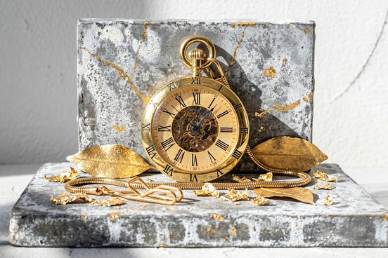 Montre gousset squelette dorée Roaring 20s Paris avec cadran romain et mécanisme visible. Chaîne et feuilles dorées.