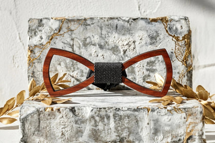 Noeud papillon en bois brun clair ajouré avec bande centrale noire texturée, style bohème chic.