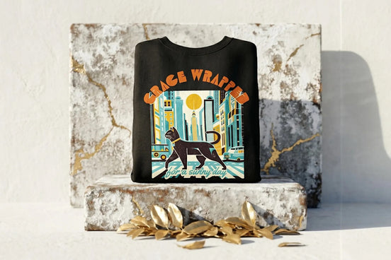 Roaring 20s Paris sweat col rond noir avec illustration de chat noir dans une ville ensoleillée et chat blanc dans un ciel étoilé.